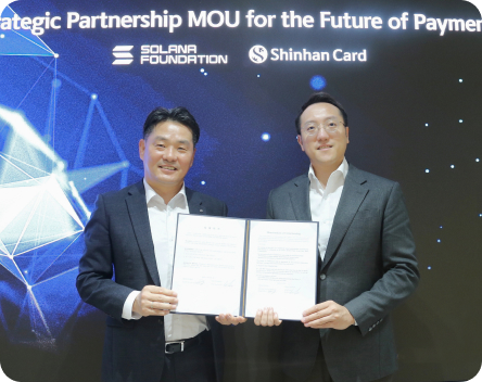 Strategic Partnership MOU for the Future of Payments 가 쓰여진 배경 앞에 SOLANA FOUNDATION과 Shinhan Card의 임직원2명이 MOU 협약서를 들고 있다.
